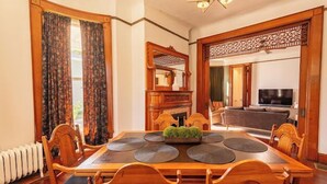 Un comedor con mesa y sillas de madera, una chimenea y un televisor en la sala de estar contigua.