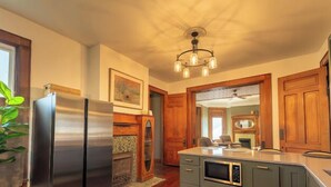 Una cocina con un refrigerador de acero inoxidable, gabinetes de madera, un microondas integrado y un ventilador de techo.
