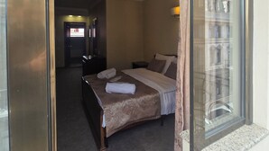 A hotel room with a large bed, a nightstand, and a view of a building through the window. - RITSA HOTEL (Batumi)