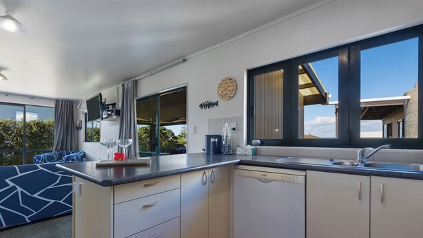 A modern kitchen with white cabinets, a dishwasher, and a large window.