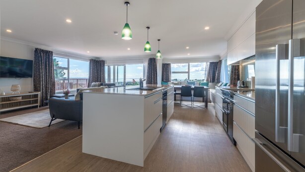 Una cocina moderna con una isla central, electrodomésticos de acero inoxidable e iluminación colgante.