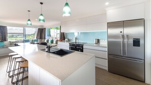 Una cocina moderna con una isla central, electrodomésticos de acero inoxidable e iluminación colgante.