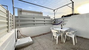Eine Dachterrasse mit Tisch und Stühlen, einer Weinflasche und Blick auf die Stadt.