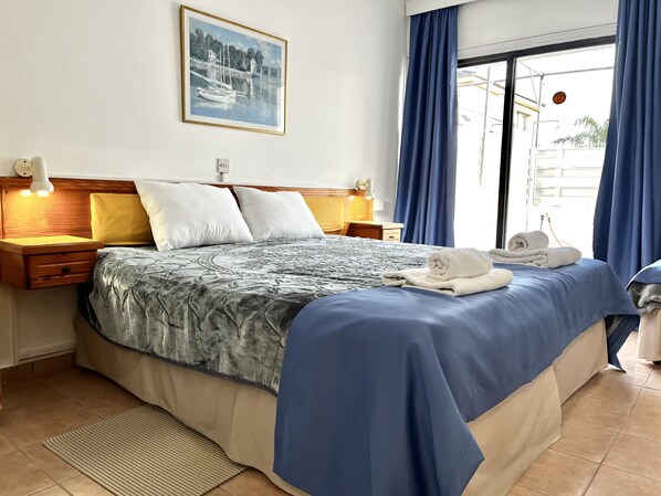 A neatly made bed with a patterned bedspread, two bedside lamps, and a framed picture on the wall.