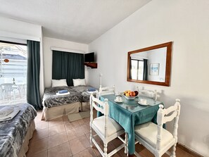 A hotel room with two beds, a dining table with chairs, a TV, and a window with curtains. - 79 AN - Stay Nissi Chrysland Studio 110 (Ayia Napa)