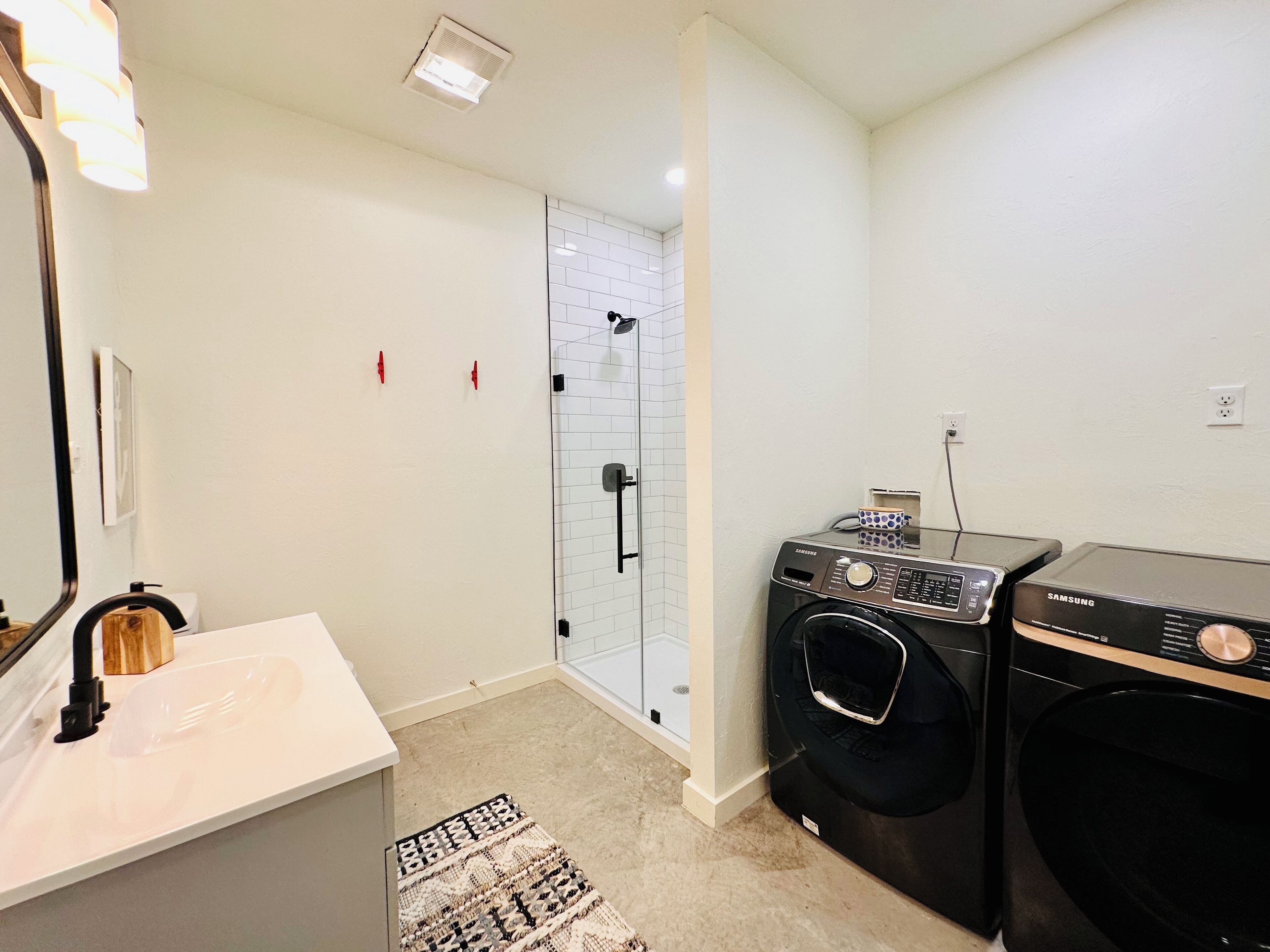 Un baño moderno con lavamanos blanco, espejo y cabina de ducha de vidrio.