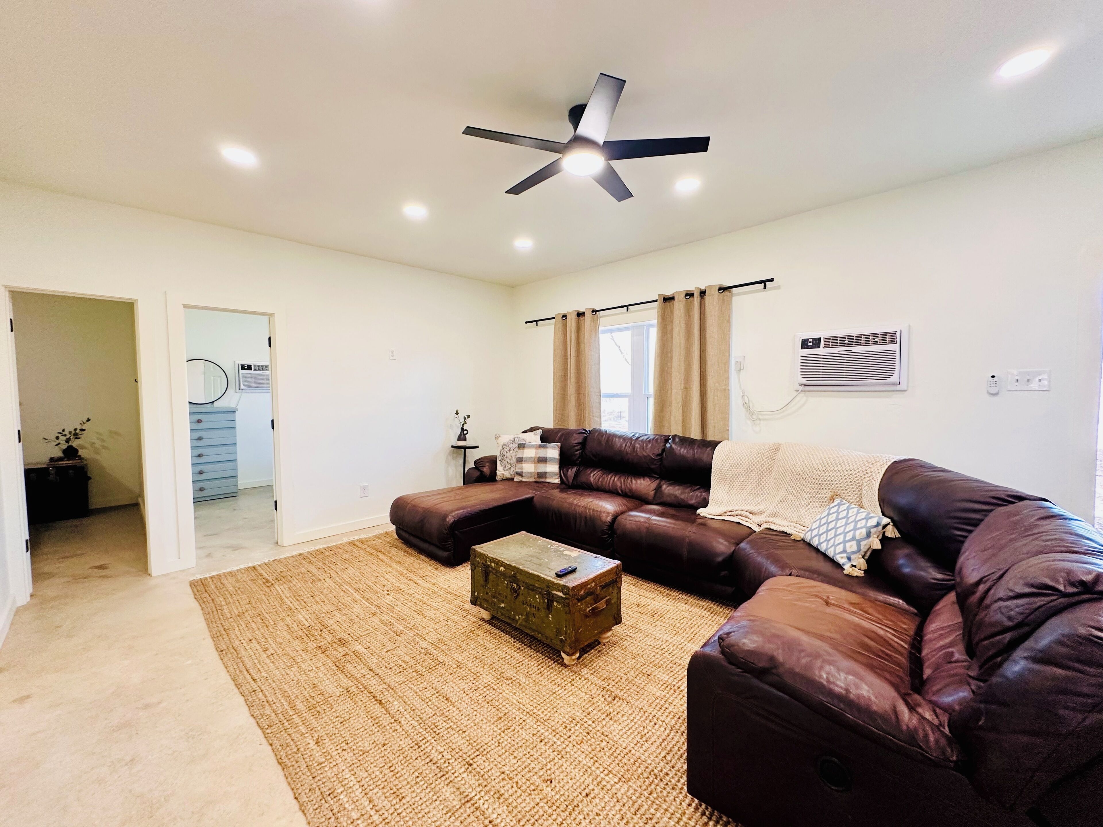 A modern living room with a sectional sofa, a coffee table, and a ceiling fan.