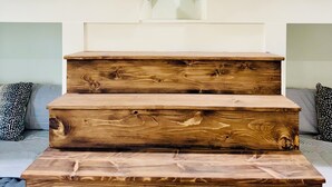 Una escalera con escalones de madera que lleva a una zona con cama elevada.