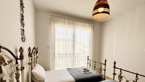 A bedroom with two beds, a balcony, and a hanging light fixture.