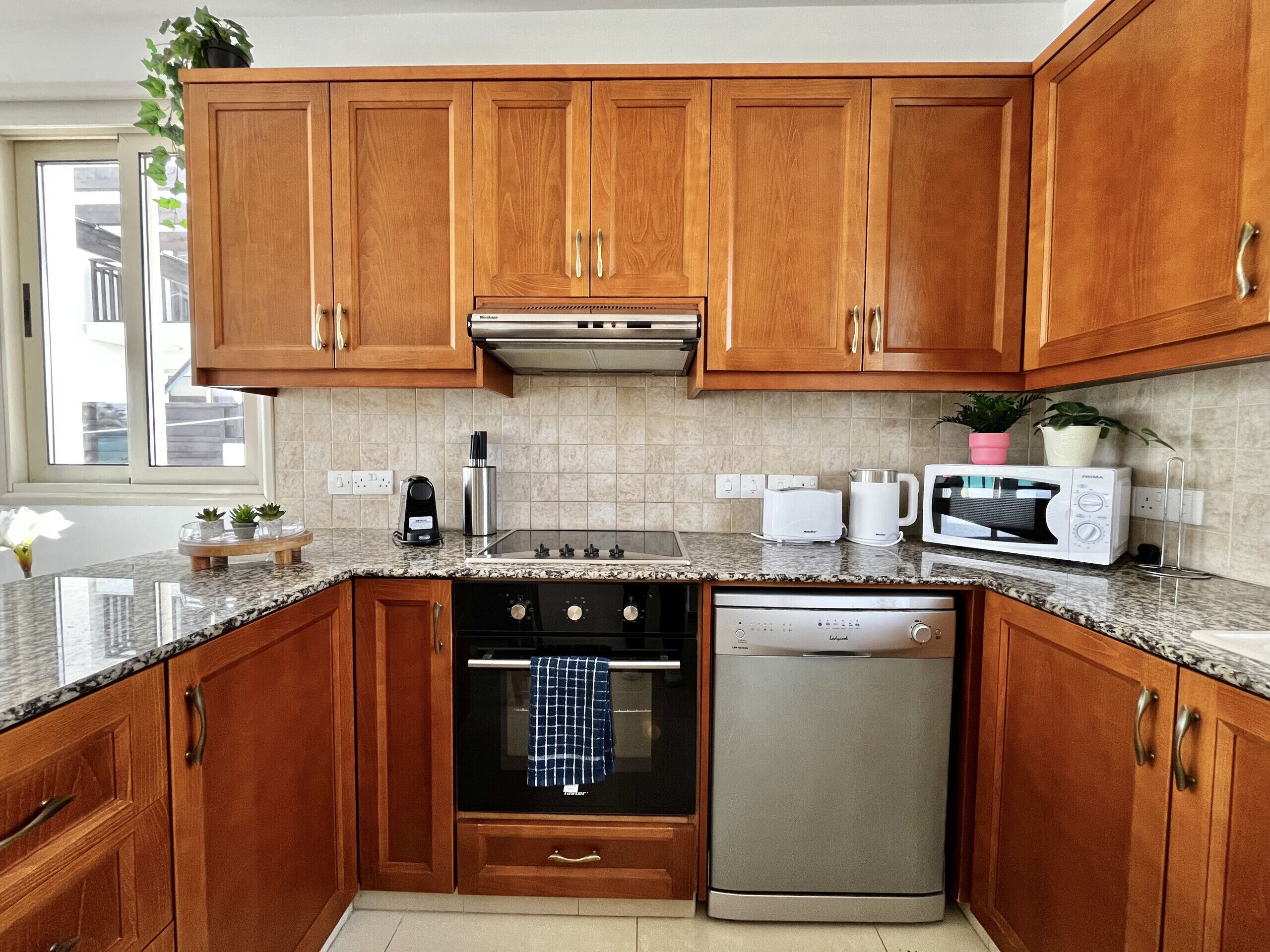 A kitchen with wooden cabinets, a stainless steel oven, a dishwasher, and a microwave.
