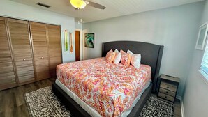 A bedroom with a bed, a wardrobe, a nightstand, and a painting on the wall. - The Lighthouse - Steps from Beach (Fort Myers Beach)