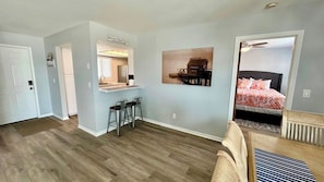 Un espacio habitable compacto con kitchenette, comedor y dormitorio con cama y ventilador de techo.