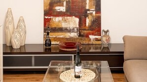 A modern living room with a glass coffee table, abstract painting, decorative vases, and a sofa. - Poznań Grunwald - 51m2, Balcony - by Rentujemy (Poznan)
