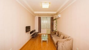 A living room with a sofa, a coffee table, a TV, and a radiator. - Lin Luo Hotel (Shijiazhuang Time Street) (Shijiazhuang)