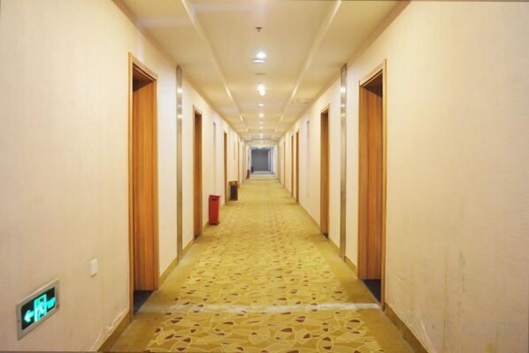 A hotel hallway with doors on both sides, a patterned carpet, and a light switch on the wall. - Lin Luo Hotel (Shijiazhuang Time Street) (Shijiazhuang)