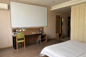 Habitación de hotel con cama, escritorio con silla, un ventanal grande y una puerta que da a otra habitación.