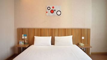 A hotel room with a large bed, two bedside tables, and a wall-mounted artwork.