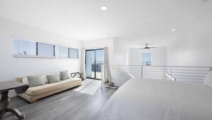 Een moderne hotelkamer met een groot bed, een bank, een eettafel en een balkon met uitzicht.
