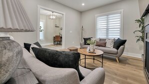 Una sala de estar moderna con un sofá gris, una mesa de centro redonda y una lámpara.
