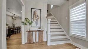 Un interior moderno con una escalera, un comedor y un pasillo que lleva a una habitación.
