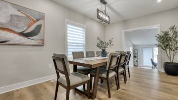 Un coin repas avec une table en bois, six chaises, un vase et une plante en pot.