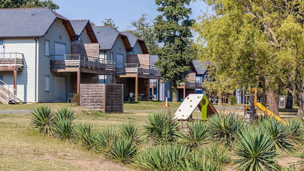 Zona residencial con casas modernas que tienen balcones y un parque infantil con un tobogán.
