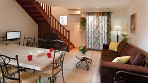 Un comedor con escalera de madera, una mesa con sillas, un sofá y una lámpara.