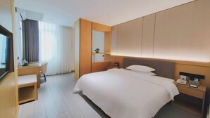 A modern hotel room with a large bed, a desk, and a chair. - XinzhuXuan Hotel (Haikou Longhu Tianshi Park Shop) (Haikou)