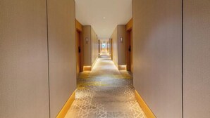 A long, narrow hotel corridor with a patterned carpet and beige walls. - XinzhuXuan Hotel (Haikou Longhu Tianshi Park Shop) (Haikou)