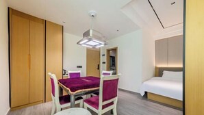 A hotel room with a bed, a dining table with chairs, a small round table, and a wardrobe. - XinzhuXuan Hotel (Haikou Longhu Tianshi Park Shop) (Haikou)
