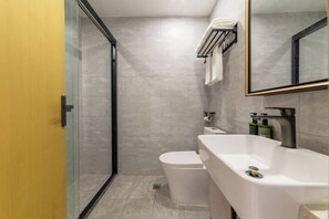 A modern bathroom with a glass shower enclosure, a white toilet, and a large sink with a mirror above. - XinzhuXuan Hotel (Haikou Longhu Tianshi Park Shop) (Haikou)