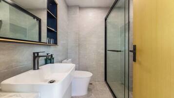 Un baño moderno con una bañera grande, un inodoro y una cabina de ducha de vidrio.