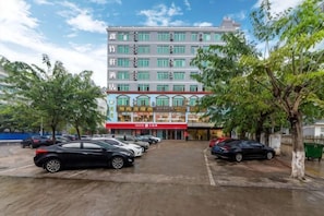 Un hôtel doté d’un parking, de plusieurs voitures et d’un bâtiment surmonté d’un auvent rouge.