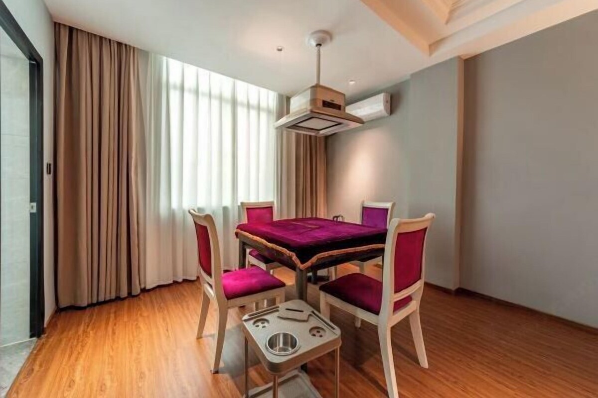 Un comedor con una mesa y cuatro sillas, una lámpara en el techo y una ventana con cortinas.