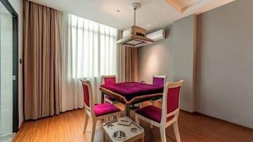 Un comedor con una mesa y cuatro sillas, una lámpara en el techo y una ventana con cortinas.