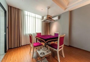 Un comedor con una mesa y cuatro sillas, una lámpara en el techo y una ventana con cortinas.