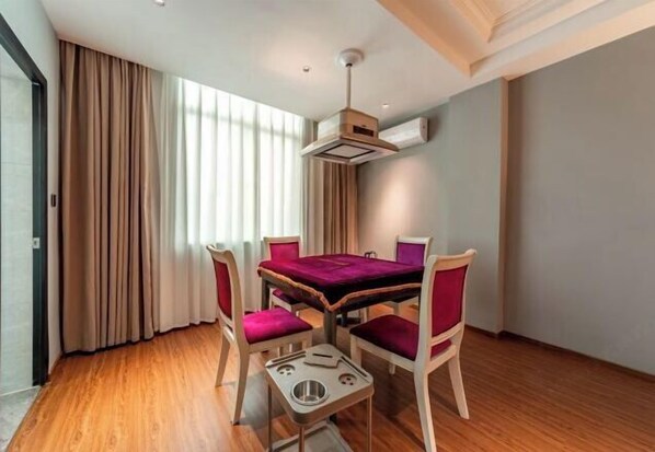 Un comedor con una mesa y cuatro sillas, una lámpara en el techo y una ventana con cortinas.