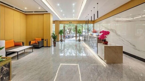 A modern lobby with a marble reception desk, seating area with orange cushions, and a glass partition. - XinzhuXuan Hotel (Haikou Longhu Tianshi Park Shop) (Haikou)