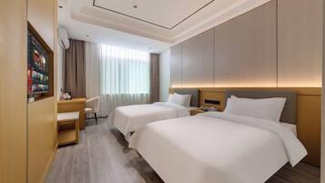 A hotel room with two beds, a desk, a chair, and a large window with curtains.