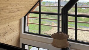 A room with a sloped ceiling, large windows, and a hanging light fixture. - Atypical chalet in the heart of the Auvergne volcanoes (Saint-Genès-Champespe)