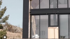 A modern house with a large glass window and a wooden door. - Atypical chalet in the heart of the Auvergne volcanoes (Saint-Genès-Champespe)