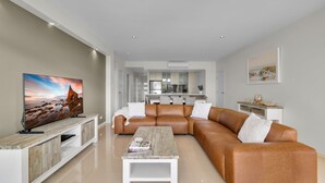 A modern living room with a leather sofa, a coffee table, and a flat-screen TV. - Our Beach House at Husky by Book Jervis Bay - Coastal Couples Escape (Huskisson)