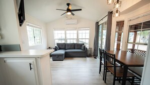 A spacious kitchen with a grey sectional sofa, wooden dining table, and chairs.