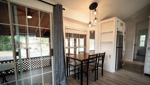A modern kitchen with wooden flooring, a dining table with chairs, and a built-in refrigerator.