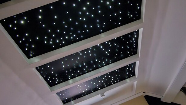 A room with a ceiling featuring a starry light installation, a flat-screen TV, and a small table with a remote control. - L'Hortillon (Amiens)