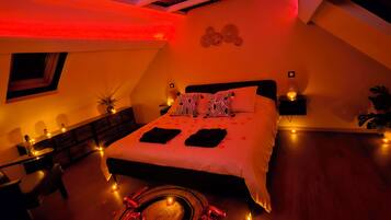 Een slaapkamer met een bed, nachtkastjes, een stoel en een tafeltje met decoratieve objecten.