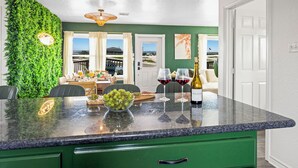 A kitchen with a green countertop, a bowl of grapes, and two wine glasses. - Views! Beachside home with private deck with soft Water / RO drinking water (Surfside Beach)