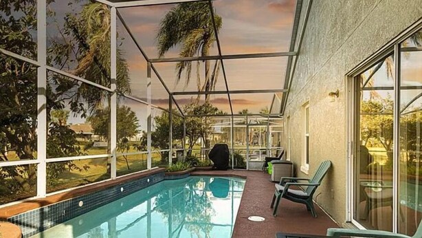 An indoor swimming pool with glass walls, a covered patio area, and outdoor views. - Luxe Lakeside Escape (Davenport)