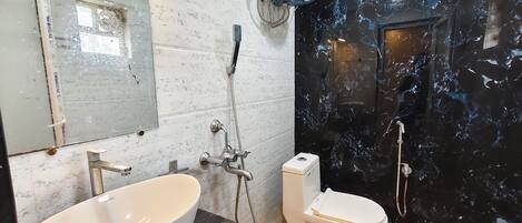 A bathroom with a large white basin, a toilet, and a shower area.
