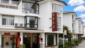 A hotel with a traditional architectural style, featuring a prominent red signboard, multiple windows, and a balcony. - Yixin Homestay (Wuyishan)